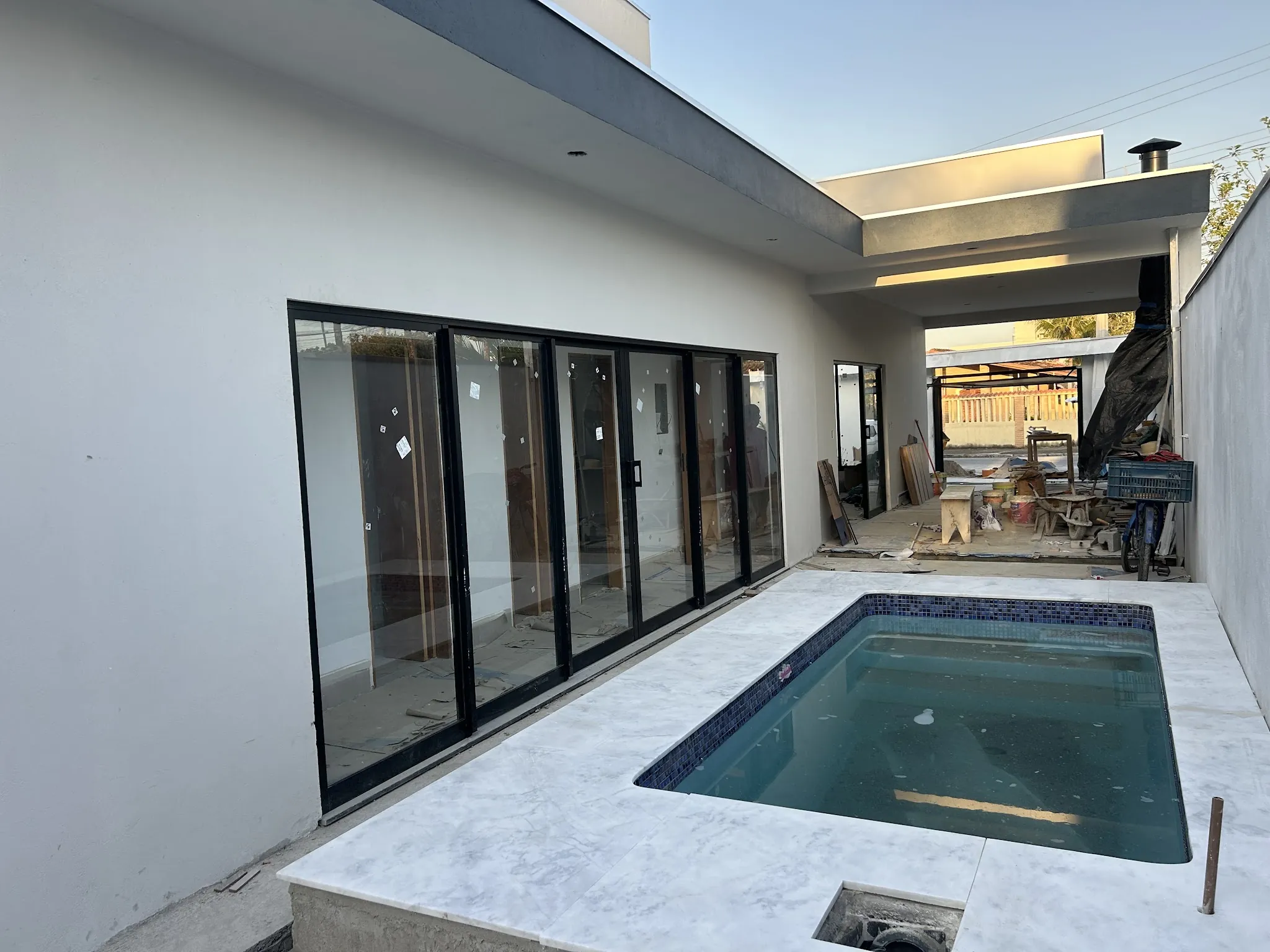 Área de lazer com piscina e portas de vidro, obra entregue